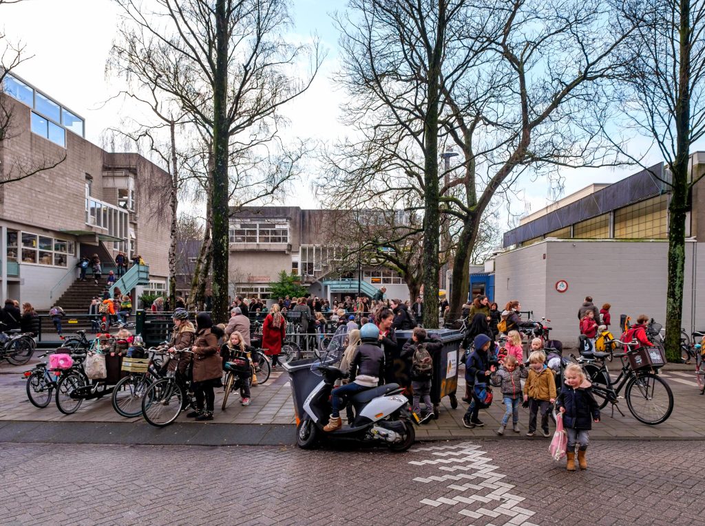 Foto van een schoolplein tijdens het uitgaan van een school. Sfeerbeeld bij een intro over schooladviezen van basisscholen.