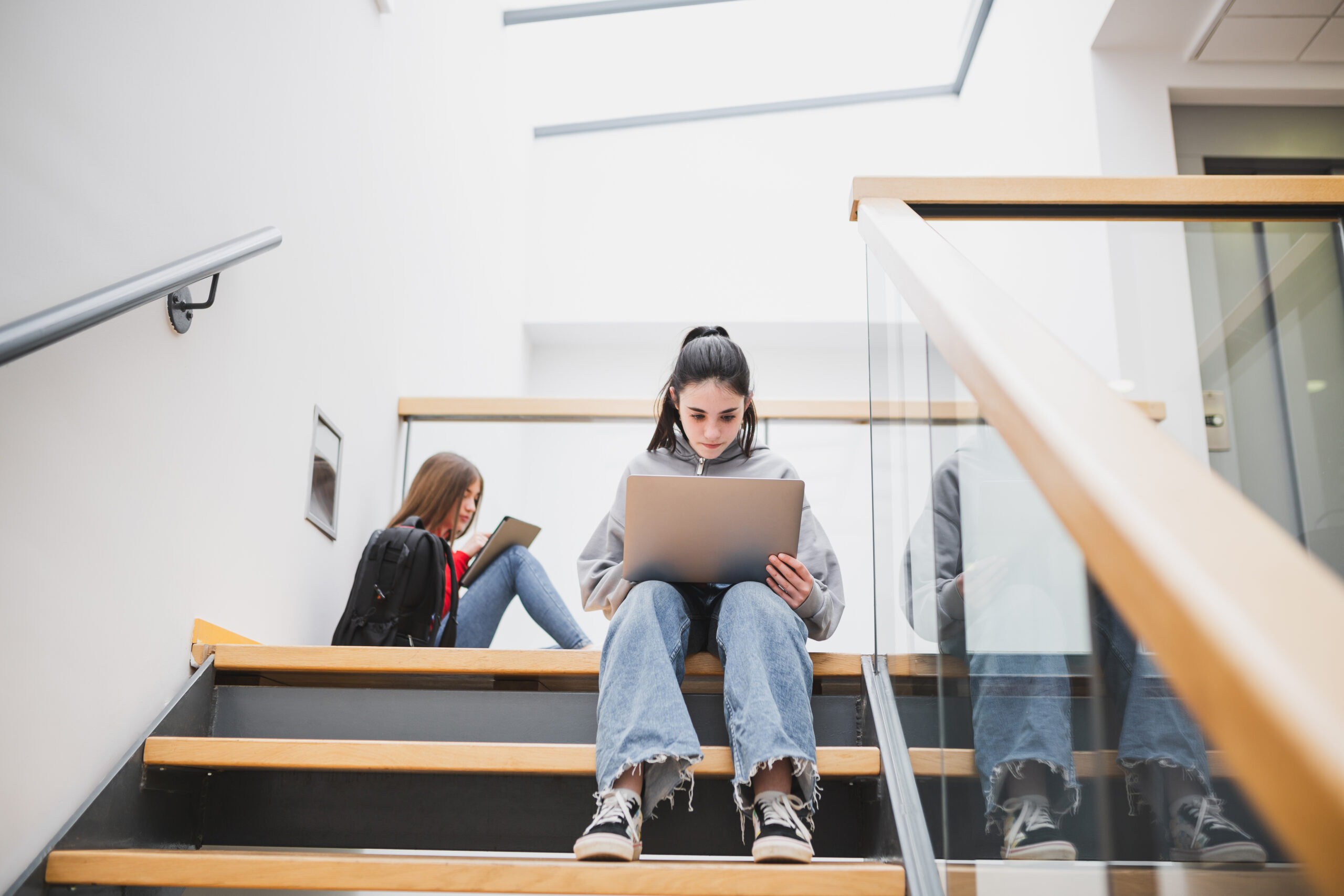 Foto van een studente op de trap van een schoolgebouw. Sfeerbeeld bij een intro voor een case over Koers VO, een samenwerkingsverband in de regio Rotterdam.